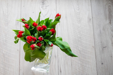 red tulips in a vase on a wooden background