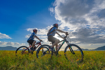Naklejka na ściany i meble couple lover enjoy riding mountain bicyble adventure touring on the grass meadow at holidays weeken together exercise