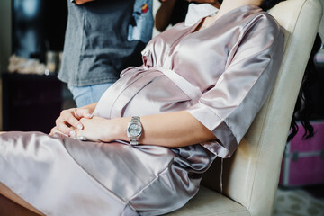 pregnant lady holding hands on babybump in elegant dress