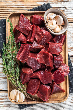 Raw sliced Beef or veal heart in a wooden tray with thyme. White wooden background. Top View