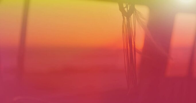 Animation of dream catcher moving in wind with yellow to red hue with sunset in background