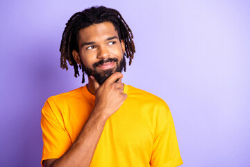 Portrait of nice optimistic brunette hairdo guy look empty space wear orange t-shirt isolated on lilac color background
