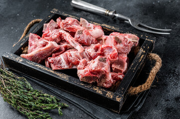 Raw diced meat with bone in a wooden tray. Black background. Top View