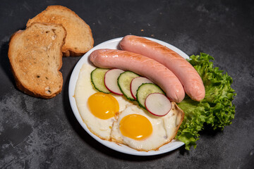 Two fried eggs and sausages, lettuce, cucumber and radish slices on a white plate, toast. Scrambled eggs. Breakfast. Healthy eating. Close-up