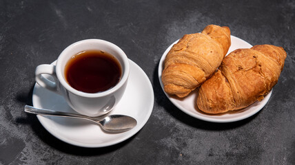 Tea or coffee on a saucer in a white cup with croissants. Breakfast. Close-up. Selective focus.
