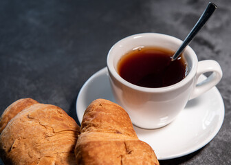 Tea or coffee on a saucer in a white cup with croissants. Breakfast. Close-up. Selective focus.