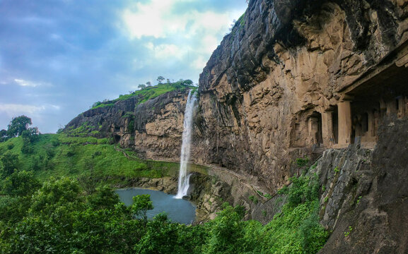 Beautiful waterfall cascading near the rock-cut Ellora Caves in Aurangabad, surrounded by lush greenery, dark basalt cliffs, and centuries-old historic architecture.
