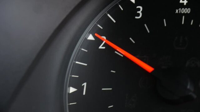 Close-up of the tachometer, RPMS gauge on the dash of a car as the engine revs.