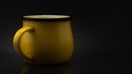 Studio shot of a ceramic yellow mug isolated on a dark background © Cristian Muñoz Gallardo/Wirestock