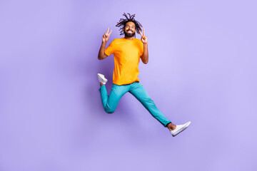 Full size photo of nice optimistic brunet guy jump show v-sign wear t-shirt pants isolated on lilac color background