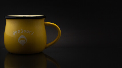 Close up side shot of a yellow mug isolated on a dark background © Cristian Muñoz Gallardo/Wirestock