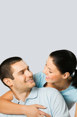 Smiling happy amazed couple. Portrait image of standing close caucasian models in love studio concept, isolated on grey color background. Young man and woman posing together. Copy space.