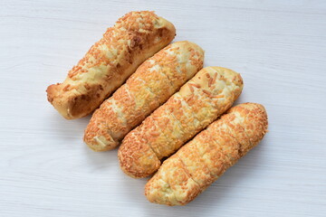 Puff pastry cheese stick, decorated with Parmesan cheese on white wooden background