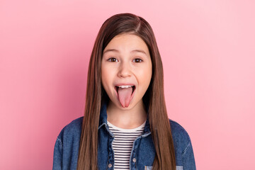 Photo portrait of wearing jeans jacket little girl grimacing showing tongue isolated on pastel pink...
