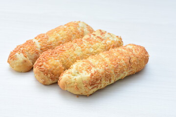 Puff pastry cheese stick, decorated with Parmesan cheese on white wooden background