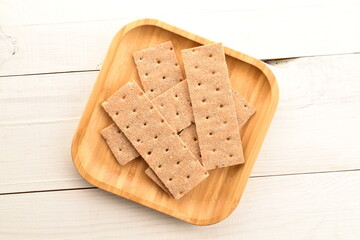 Several light brown multi-grain rye crispbreads in a bamboo plate, close-up, on a wooden table, top view.