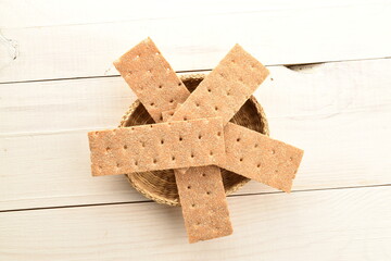 Several light brown multi-grain rye crispbreads in straw dishes, close-up, on a wooden table, top view.