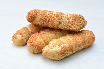 Puff pastry cheese stick, decorated with Parmesan cheese on white wooden background