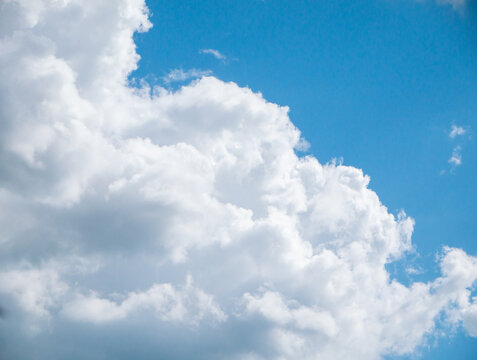 Large and voluminous white fluffy clouds in a bright blue sky in clear weather