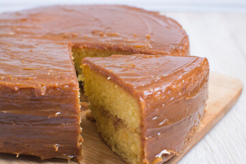 Large vanilla cake, decorated with arequipe on wooden background