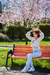 Portrait of a woman sitting on a bench in the park on a beautiful spring day.