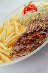 Pork with french fries and cabbage salad with bell peppers.