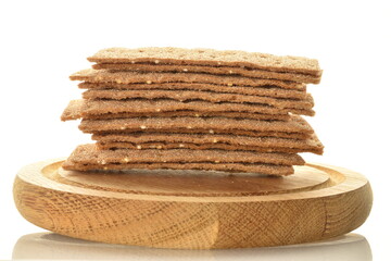 Light brown multi-grain rye crispbread on a round wooden tray, close-up, isolated on white.