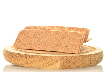 Light brown multi-grain rye crispbread on a round wooden tray, close-up, isolated on white.