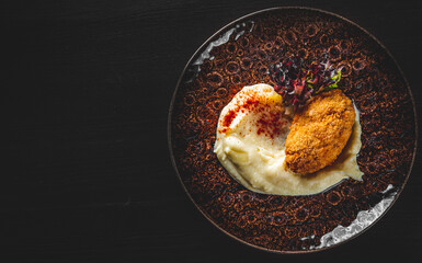 burger with mashed potatoes in white on black wooden background