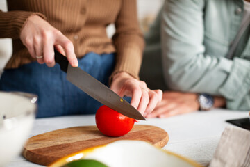 Close up of woman cutting tomato. Woman making salad.