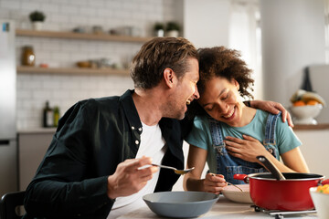 Boyfriend and girlfriend eating lunch with friends at home. Young couple enjoying the company of their friends.