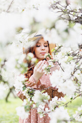 Red-haired girl walks in a spring blooming apple orchard