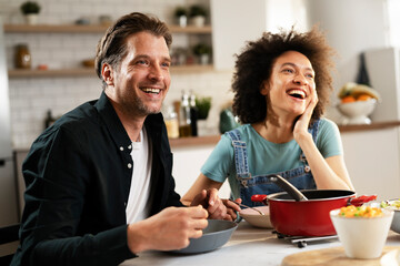 Boyfriend and girlfriend eating lunch with friends at home. Young couple enjoying the company of their friends.