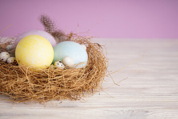 Easter eggs in a nest on wooden background, space for text.