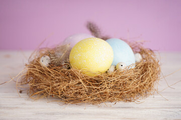 Easter eggs in a nest on a wooden background, close-up.