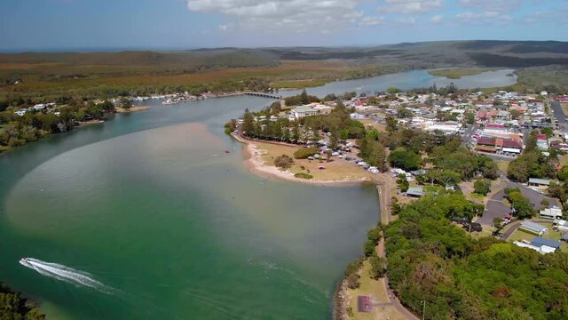 Aerial view overlooking a boat on a river, at the Evans Head village, New South Wales, Australia - reverse, drone shot