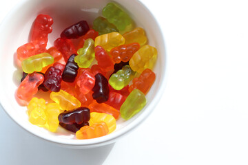 Multicolored gummy bears in bowl on white background. Top view, copy space. Flat lay food. Chewing gummies on plate