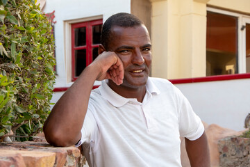 Portrait of a smiling dark-skinned man of 40 years on the background of beautiful buildings, close-up. Perhaps he works as a lifeguard or tourist guide, service personnel.