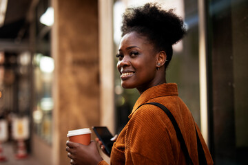 Young african woman outdoors. Beautiful woman with messy hair drinking coffee.