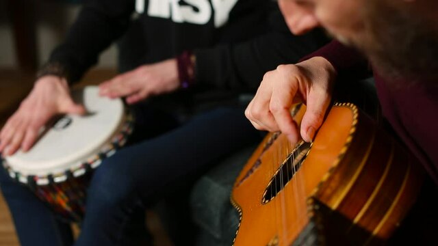 The hand of a musician plays the guitar. Musicians hands make music. Creating a new album. The man bangs the jambe drum with his hands.