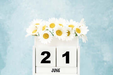 cube calendar for June with daisy flowers over blue with copy space