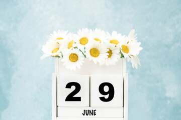 cube calendar for June with daisy flowers over blue with copy space