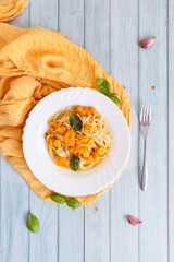 Pasta, spaghetti with yellow tomato in white plate. Blue background. Top view. Close up.