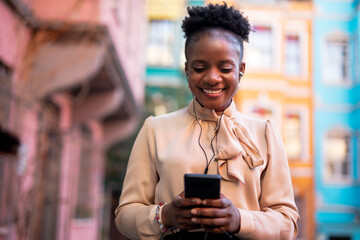 Young african woman outdoors. Beautiful woman with curly hair using the phone.