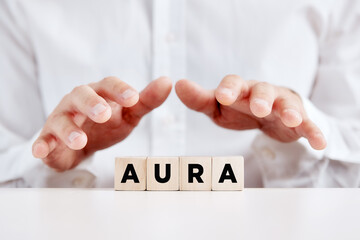 Man holding his hands protectively over the wooden cubes with the word aura.