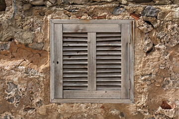 rustic wooden shutter in stone wall