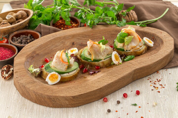 Tasty bruschetta with pork, egg and cucumber on wooden plate on the table