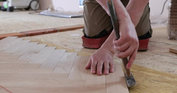 close up of man installing wood flooring. Construction in a renovated room installation of parquet.