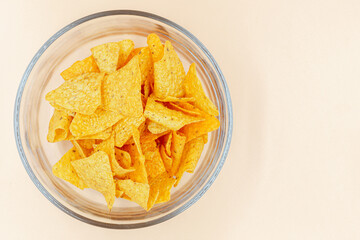 Corn chips into a glass bowl, nachos isolated on orange  background with copy space ,Top view 