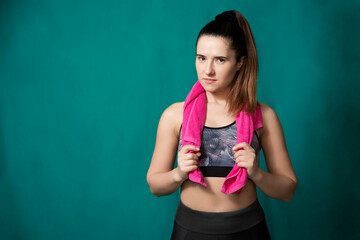 Photo of young woman in sportswear on dark green background.